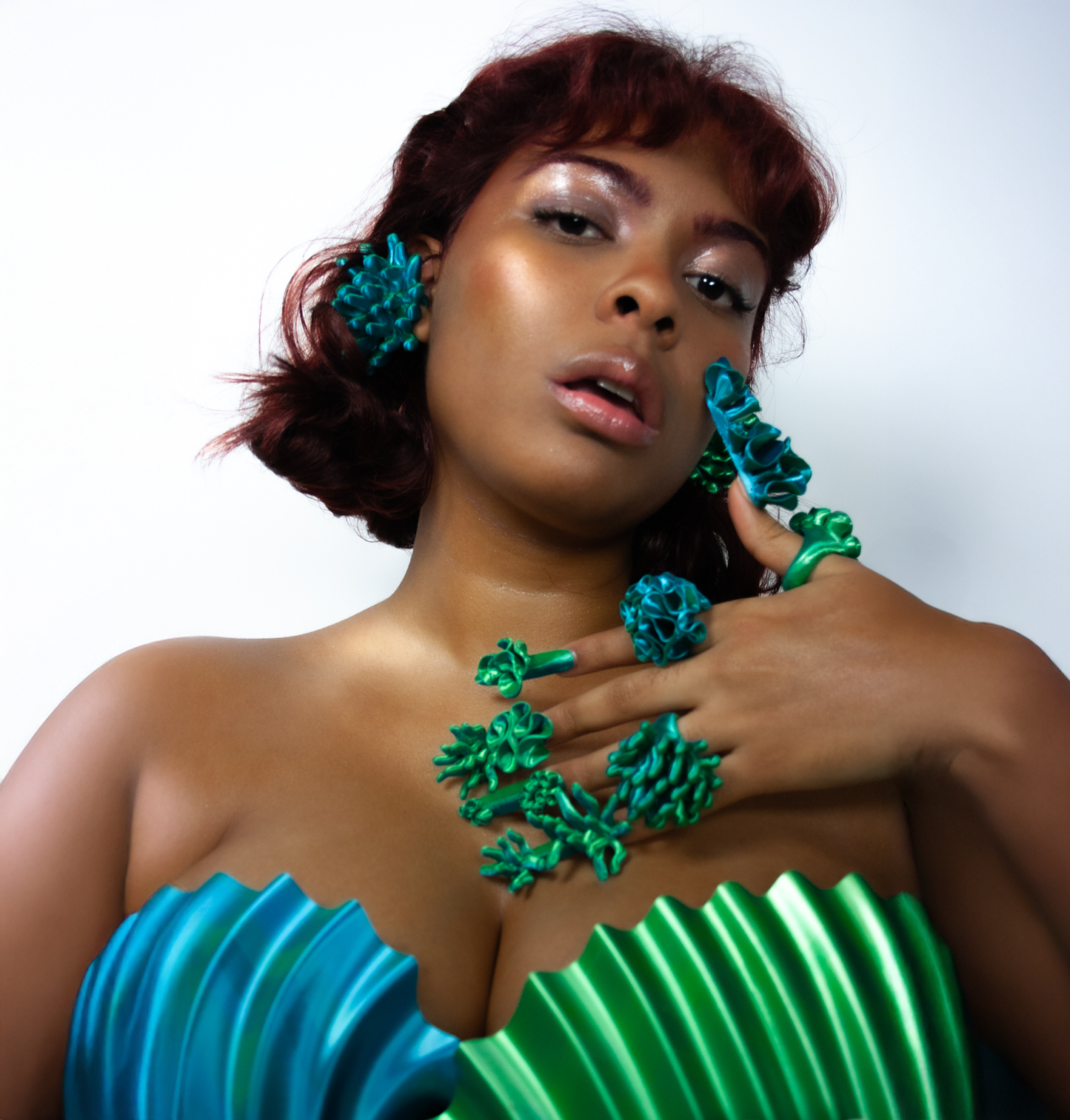 A close-up shot of a muse wearing the green Anemone and Marina rings, alongside Anemone earrings from Bhumi's 'Bathe in the Waters' collection. The 3D-printed coral-inspired accessories highlight intricate textures and bold design, exuding an ethereal, organic energy.