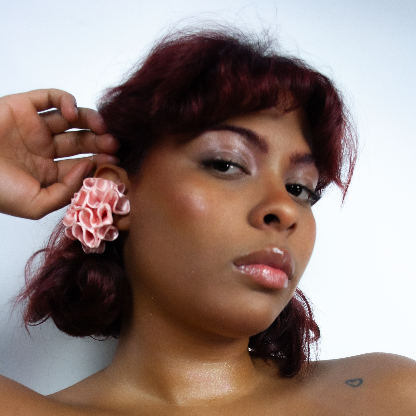 A close-up of a muse wearing the Marina earcuff in satin baby pink from Bhumi's debut collection 'Bathe in the Waters.' This bold, coral-inspired 3D-printed accessory exudes movement and delicate femininity.